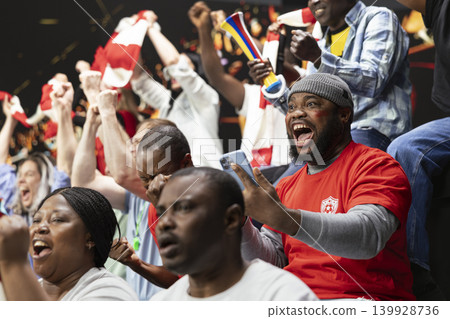 Excited football supporter celebrating live bet win on his phone, dramatic soccer match in a stadium. Happy fan reacts with shock and adrenaline, big payout jackpot lucky win for sports betting. Excited football supporter celebrating live bet win on his phone, dramatic soccer match in a stadium. Happy fan reacts with shock and adrenaline, big payout jackpot lucky win for sports betting. 139928736