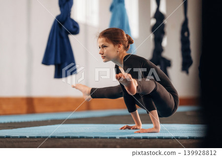Routine exercise for the strong arms. Child practicing yoga on a mat in a fitness studio Routine exercise for the strong arms. Child practicing yoga on a mat in a fitness studio 139928812