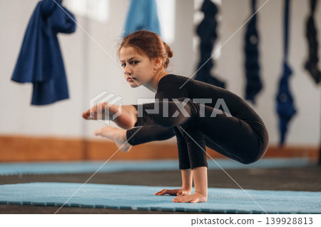 Routine exercise for the strong arms. Child practicing yoga on a mat in a fitness studio Routine exercise for the strong arms. Child practicing yoga on a mat in a fitness studio 139928813