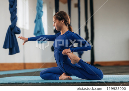 Child practicing yoga on a mat in a fitness studio Child practicing yoga on a mat in a fitness studio 139928900