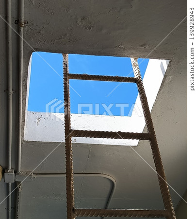 Rusted ladder reaching toward a frame of endless blue Rusted ladder reaching toward a frame of endless blue 139928943