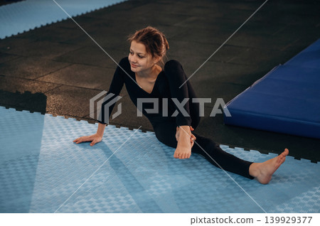 Child practicing yoga on a mat in a fitness studio Child practicing yoga on a mat in a fitness studio 139929377