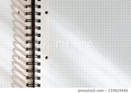 Blank white squared notebook page with metallic spiral binding background with lights and shadows. template mockup 139929480