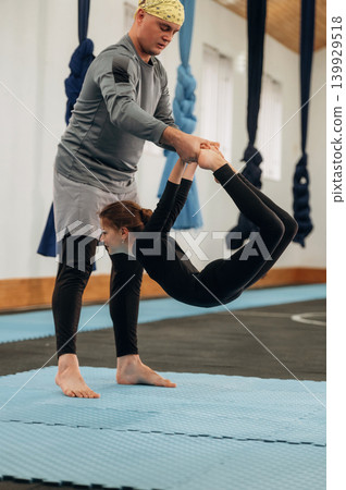 Black color hammock straps. Male instructor assisting a child in aerial yoga practice in a fitness studio Black color hammock straps. Male instructor assisting a child in aerial yoga practice in a fitness studio 139929518
