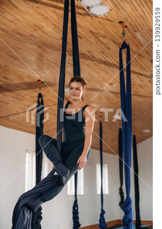 Woman practicing aerial yoga on hammock straps in a fitness studio Woman practicing aerial yoga on hammock straps in a fitness studio 139929559