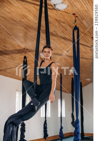 Woman practicing aerial yoga on hammock straps in a fitness studio Woman practicing aerial yoga on hammock straps in a fitness studio 139929560