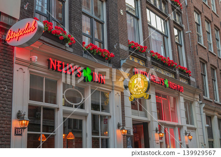 Amsterdam, Netherlands, 22.04.2026 - Traditional Irish pub facade with neon signs and flower decorated windows in European city Amsterdam, Netherlands, 22.04.2026 - Traditional Irish pub facade with neon signs and flower decorated windows in European city 139929567