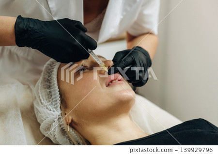 Making the lips bigger. Cosmetologist performing a facial injection procedure in a beauty clinic Making the lips bigger. Cosmetologist performing a facial injection procedure in a beauty clinic 139929796
