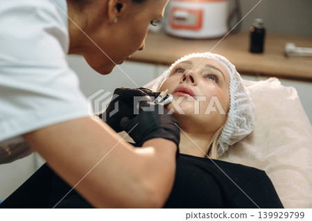 Making the lips bigger. Cosmetologist performing a facial injection procedure in a beauty clinic Making the lips bigger. Cosmetologist performing a facial injection procedure in a beauty clinic 139929799