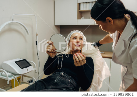 In black gloves. Female cosmetologist performing a facial skincare procedure using a cosmetic device in a beauty clinic In black gloves. Female cosmetologist performing a facial skincare procedure using a cosmetic device in a beauty clinic 139929801