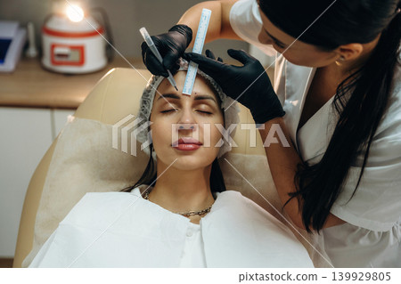 Marking the place. Female cosmetologist performing a facial skincare procedure using a cosmetic device in a beauty clinic Marking the place. Female cosmetologist performing a facial skincare procedure using a cosmetic device in a beauty clinic 139929805