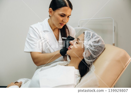 Client is lying down. Female cosmetologist performing a facial skincare procedure using a cosmetic device in a beauty clinic 139929807