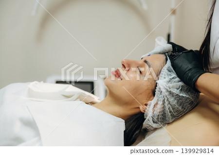 Rejuvenation process. Facial skincare treatment with a cosmetic device in a beauty clinic Rejuvenation process. Facial skincare treatment with a cosmetic device in a beauty clinic 139929814