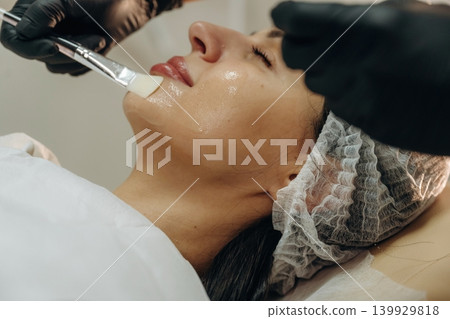 Brush, applying cream with it. Close-up of a facial skincare treatment with a cosmetic device in a beauty clinic Brush, applying cream with it. Close-up of a facial skincare treatment with a cosmetic device in a beauty clinic 139929818