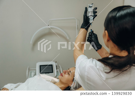Taking the product by syringe. Cosmetologist performing a facial injection procedure in a beauty clinic Taking the product by syringe. Cosmetologist performing a facial injection procedure in a beauty clinic 139929830