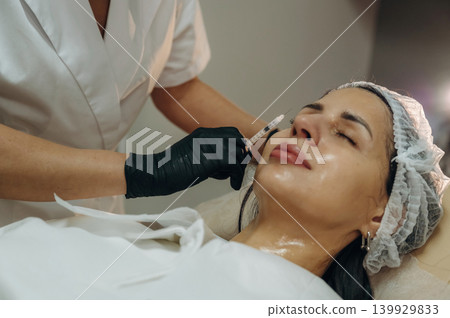 Ready to penetrate the skin. Cosmetologist performing a facial injection procedure in a beauty clinic Ready to penetrate the skin. Cosmetologist performing a facial injection procedure in a beauty clinic 139929833