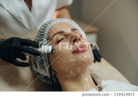 With eyes closed. Close-up of a facial skincare treatment with a cosmetic device in a beauty clinic With eyes closed. Close-up of a facial skincare treatment with a cosmetic device in a beauty clinic 139929855