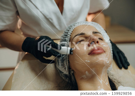 With eyes closed. Close-up of a facial skincare treatment with a cosmetic device in a beauty clinic With eyes closed. Close-up of a facial skincare treatment with a cosmetic device in a beauty clinic 139929856
