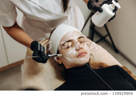 Applying the cream. Close-up of a facial skincare treatment with a cosmetic device in a beauty clinic Applying the cream. Close-up of a facial skincare treatment with a cosmetic device in a beauty clinic 139929909
