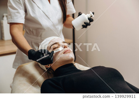 Applying the cream. Close-up of a facial skincare treatment with a cosmetic device in a beauty clinic 139929911