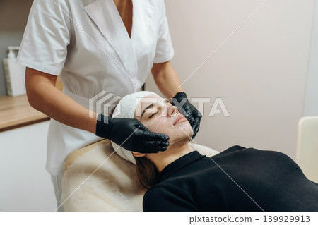 Rejuvenation process. Facial skincare treatment with a cosmetic device in a beauty clinic Rejuvenation process. Facial skincare treatment with a cosmetic device in a beauty clinic 139929913