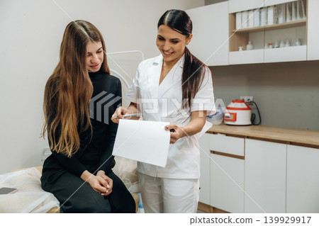 Professional cosmetologist consulting a female client about facial skincare in a beauty clinic Professional cosmetologist consulting a female client about facial skincare in a beauty clinic 139929917