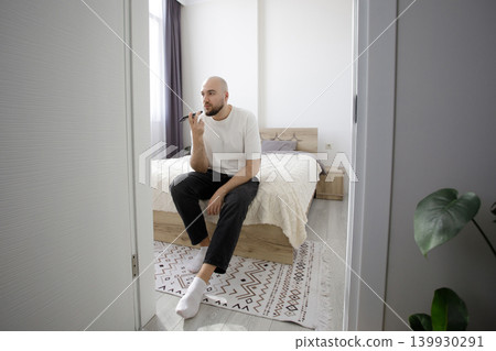 Man dictates a voice message on a smartphone at home Man dictates a voice message on a smartphone at home 139930291