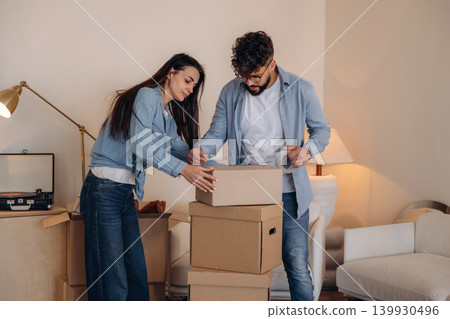 Using scotch as glue. Couple packing cardboard boxes while preparing to move into a new home Using scotch as glue. Couple packing cardboard boxes while preparing to move into a new home 139930496