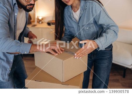 Couple packing cardboard boxes while preparing to move into a new home Couple packing cardboard boxes while preparing to move into a new home 139930578