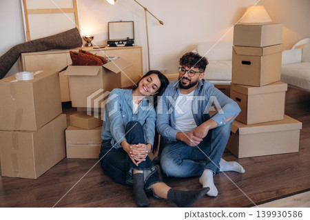 Cheerful, having fun, sitting on the floor. Playful couple enjoying time together while moving into a new home Cheerful, having fun, sitting on the floor. Playful couple enjoying time together while moving into a new home 139930586
