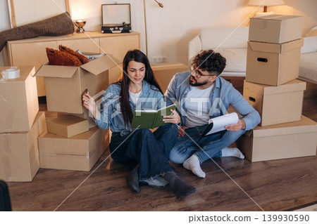 Notepad is in hands. Couple reviewing documents and planning their new home after moving Notepad is in hands. Couple reviewing documents and planning their new home after moving 139930590