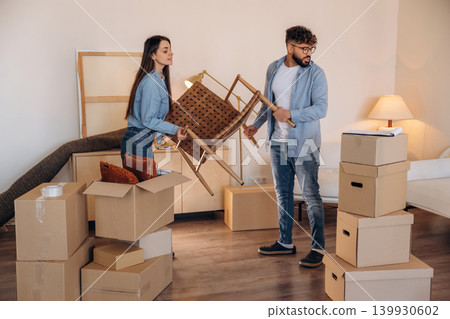 Chair is in hands. Couple packing while preparing to move into a new home Chair is in hands. Couple packing while preparing to move into a new home 139930602