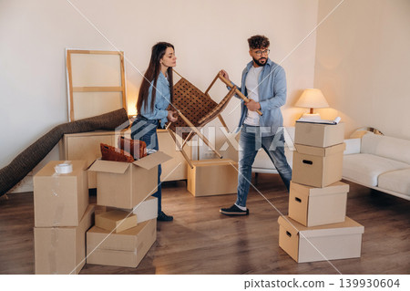 Chair is in hands. Couple packing while preparing to move into a new home Chair is in hands. Couple packing while preparing to move into a new home 139930604