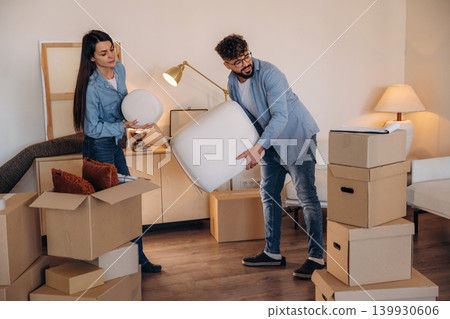 Couple packing cardboard boxes while preparing to move into a new home Couple packing cardboard boxes while preparing to move into a new home 139930606