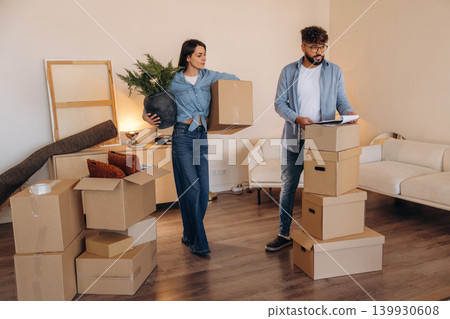 Woman is holding big green plant. Couple reviewing documents and planning their new home after moving Woman is holding big green plant. Couple reviewing documents and planning their new home after moving 139930608