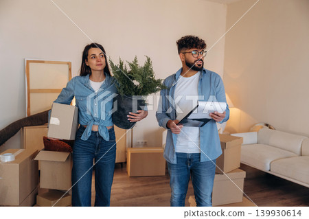 Active, with lot of stuff. Couple reviewing documents and planning their new home after moving Active, with lot of stuff. Couple reviewing documents and planning their new home after moving 139930614