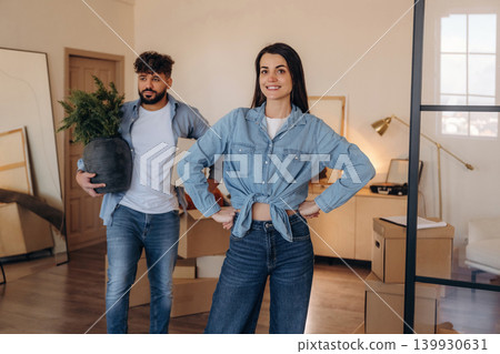 Positive couple placing a potted plant in their new apartment during the moving process Positive couple placing a potted plant in their new apartment during the moving process 139930631