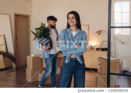 Waiting for the man to place the object. Positive couple placing a potted plant in their new apartment during the moving process Waiting for the man to place the object. Positive couple placing a potted plant in their new apartment during the moving process 139930634