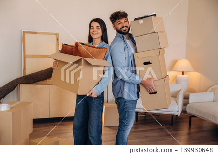Standing together. A couple carrying cardboard boxes while moving into a new apartment Standing together. A couple carrying cardboard boxes while moving into a new apartment 139930648