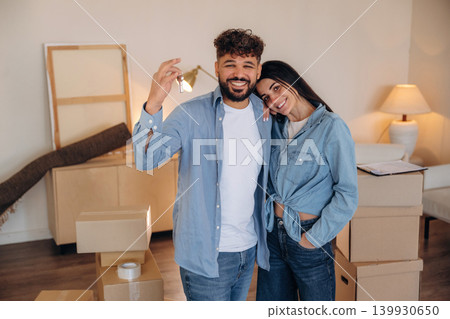 Positive facial expression. Excited couple holding house keys after moving into their new home Positive facial expression. Excited couple holding house keys after moving into their new home 139930650