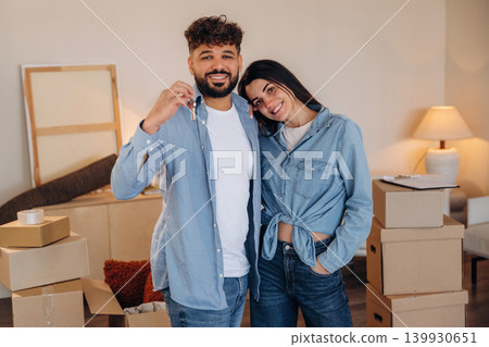 Positive facial expression. Excited couple holding house keys after moving into their new home Positive facial expression. Excited couple holding house keys after moving into their new home 139930651
