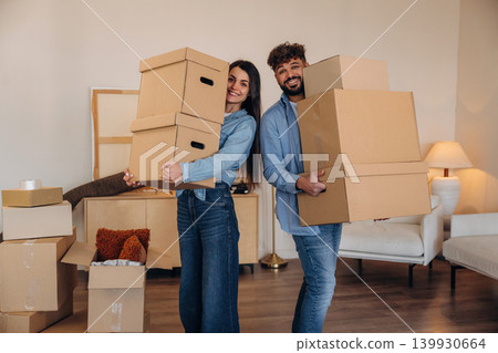 A couple carrying cardboard boxes while moving into a new apartment A couple carrying cardboard boxes while moving into a new apartment 139930664