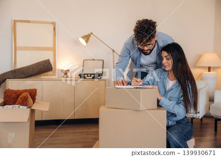 Focused, writing on the paper. Couple reviewing documents and planning their new home after moving Focused, writing on the paper. Couple reviewing documents and planning their new home after moving 139930671