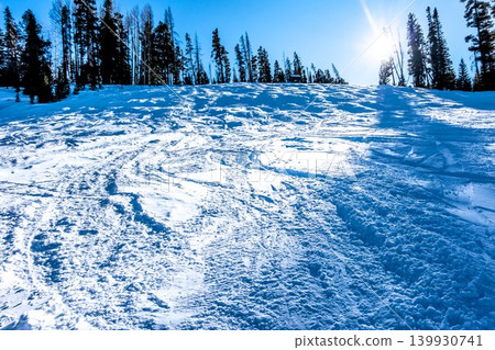 Snow Covered Ski Slope Texture with Tracks and Patterns Under Bright Sunlight Snow Covered Ski Slope Texture with Tracks and Patterns Under Bright Sunlight 139930741