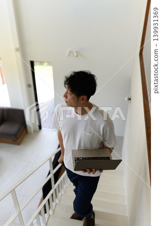 一個男人抱著筆記型電腦上樓。 139931369