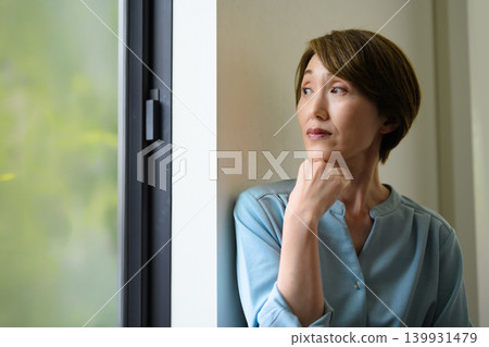 A woman looking out by the window A woman looking out by the window 139931479