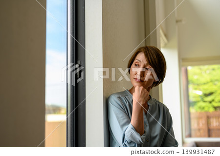 Pensive woman by the window Pensive woman by the window 139931487