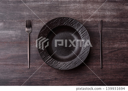 An empty ceramic round plate, kitchen utensils for a dinner table. An empty plate 139931694