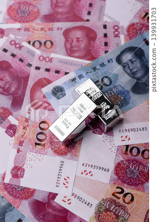 A silver bar, white metal against a backdrop of Chinese money, as a concept for the sales market A silver bar, white metal against a backdrop of Chinese money, as a concept for the sales market 139931703