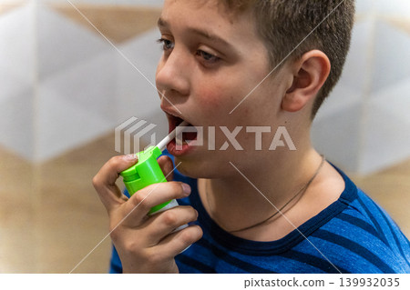Child uses green inhaler to take medication indoors during a health routine 139932035